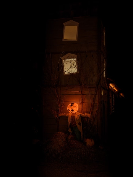 A scarecrow leans against a kids' play structure that has been turned into a Halloween-themed haunted house.